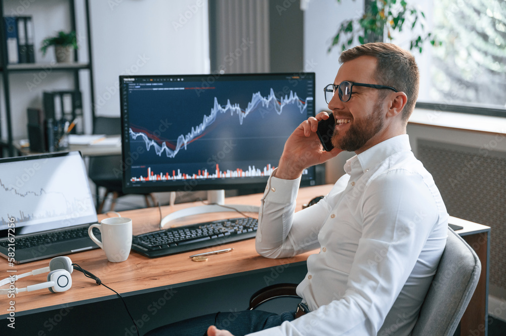 Poster stock exchange graphs on the screen. man in formal clothes is working in the modern office. using co