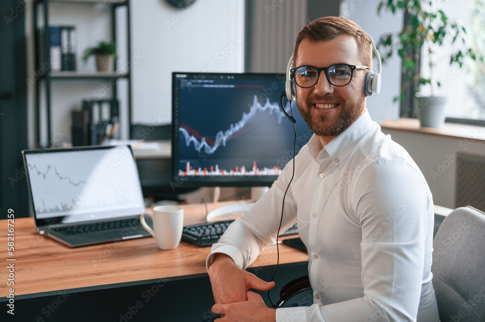 Poster stock exchange graphs on the screen. man in formal clothes is working in the modern office. using co