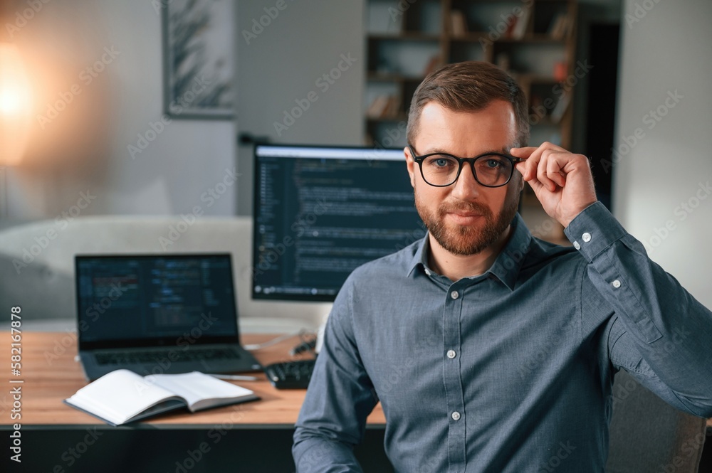 Poster software developer is sitting and posing. man in formal clothes is working in the modern office. usi