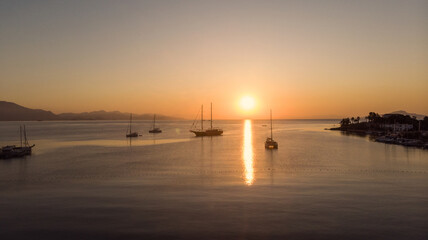 Sailboats cruising the Mediterranean coves and sunset