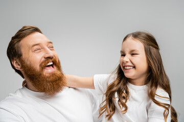 Excited kid and father in white t-shirts laughing isolated on grey.