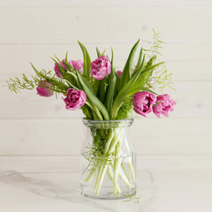 Purple bouquet of tulips on a marble table against a white wooden wall.