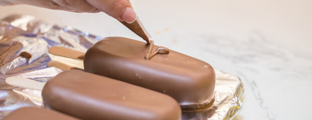 woman confectioner decorates marshmallows in chocolate on a stick. home bakery concept.