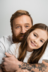 Portrait of smiling parent hugging preteen daughter isolated on grey.