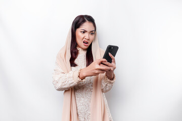 A depresses Asian Muslim woman wearing a headscarf looks stressed while talking on the phone isolated by white background