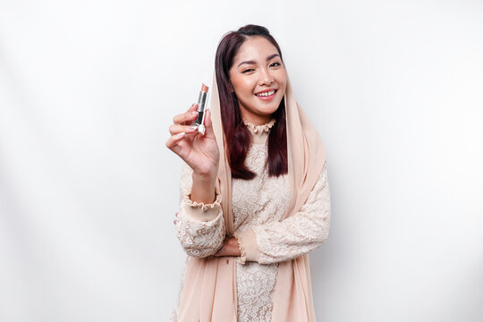Portrait of a young beautiful Asian Muslim woman wearing a headscarf holding her lipstick