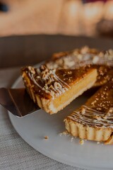 Vertical closeup of pecan pie on a white glass plate with blurred background