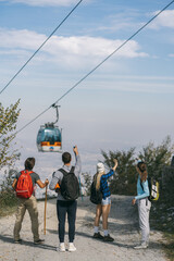 Obraz premium Four hikers looking at the zip line on top of the mountain