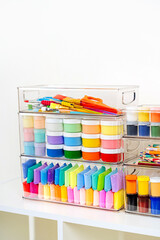 Paints, pencils, plasticine and various material for creativity and kids art activity in containers on shelves. Stationery and supplies for drawing and craft. Organizing and storage craft room.