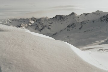 Close-up shot of a snow texture with the view on snowy hill background