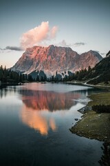 Fototapeta na wymiar Vertical shot of a lake surrounded by rocky hills during the sunset in Austria