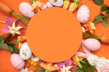 easter frame with fresh spring carrots ,easter eggs,confetti,decor on an orange background. top view. copy space. flat lay.
