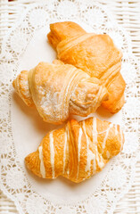 Three baked french croissants on festive white table-cloth 