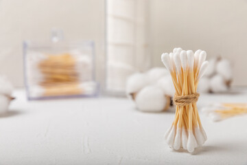 Obraz na płótnie Canvas Cotton buds on a light concrete background.Eco-friendly materials. Wooden, cotton swabs on a white background.Bamboo swabs and cotton flowers.Zero waste, plastic free lifestyle concept.Place for text.