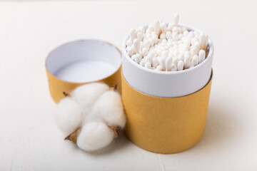 Cotton buds on a light concrete background.Eco-friendly materials. Wooden, cotton swabs on a white background.Bamboo swabs and cotton flowers.Zero waste, plastic free lifestyle concept.Place for text.