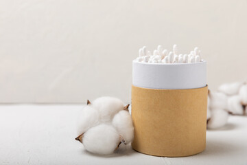 Fototapeta na wymiar Cotton buds on a light concrete background.Eco-friendly materials. Wooden, cotton swabs on a white background.Bamboo swabs and cotton flowers.Zero waste, plastic free lifestyle concept.Place for text.
