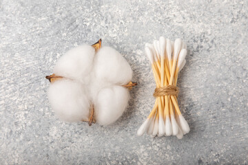Cotton buds on a light concrete background.Eco-friendly materials. Wooden, cotton swabs on a white background.Bamboo swabs and cotton flowers.Zero waste, plastic free lifestyle concept.Place for text.