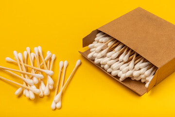 Cotton buds on a bright yellow background.Eco-friendly materials. Wooden, cotton swabs on a white background.Bamboo swabs and cotton flowers.Zero waste, plastic free lifestyle concept.Place for text.