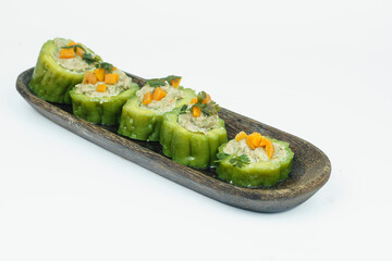 Pare or Bitter gourd stuffed with minced chicken meat served on the wooden plate.