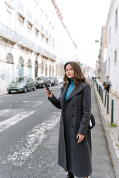 Calm woman browsing smartphone and looking away on street