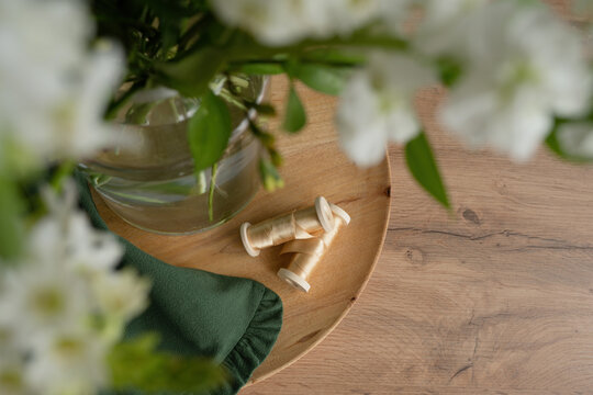 Glass vase with bouquet of flowers on board near ribbons