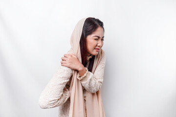 Tired upset young Asian Muslim woman wears headscarf suffering from pain, muscle spasm at...