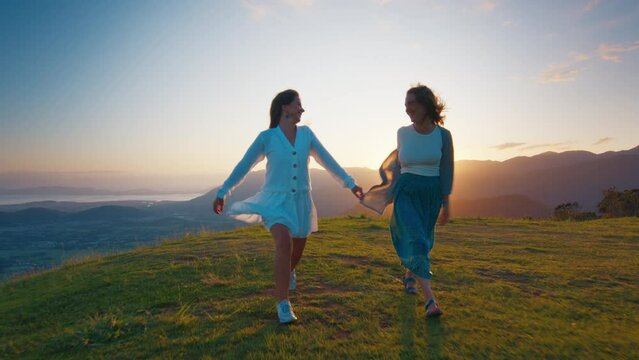Two happy woman walk and run in the mountains at sunrise