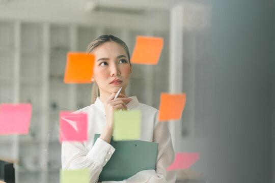 In a creative office, a startup young and confident businesswoman is strategizing using adhesive notes.
