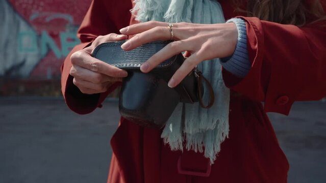 An old Soviet camera is taken out of a black case. Woman's hand raising the camera in a black case in a city in slow motion. A modern young bright girl is going to take a photo on an old camera.