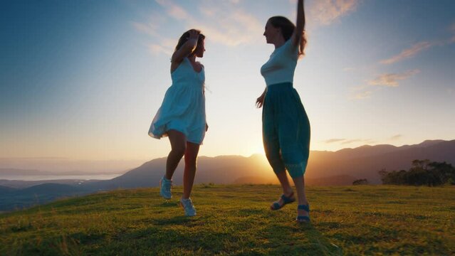 Two happy woman walk and run in the mountains at sunrise