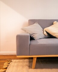 Closeup of gray couch part with pillows against a white wall
