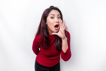 Young beautiful woman wearing a red top shouting and screaming loud with a hand on her mouth. communication concept.