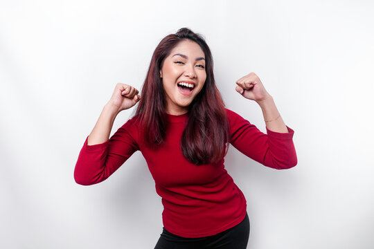 A young Asian woman with a happy successful expression wearing red top isolated by white background