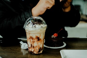 Female enjoying a delicious chocolate-flavored dessert and iced coffee cup with cream