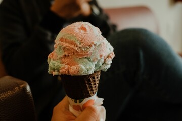 Person holding an ice cream cone with some colored topping