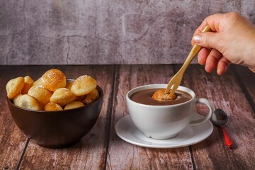 woman spreading a sugared fritter with a wooden fork on a hot chocolate