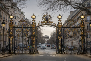 Paris, France - 03 15 2023: Parc Monceau. View of Arc de Triomphe behind the golden gate of the park