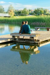 Fototapeta na wymiar young couple sitting on a bench at a lake pontoon