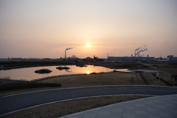 夕焼けと公園の貯水池と遠くに見える工場