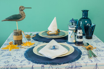 Napkin with an embroidered beacon on a plate. Blue color, marine style, table setting