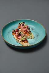 bruschetta with prosciutto on a blue plate on a blue background