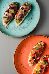 bruschetta with meat and fish on a gray background, top view