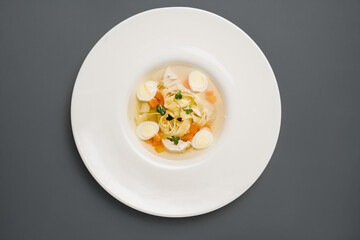 tender chicken broth with quail eggs on a white plate