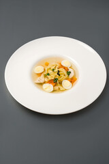 tender chicken soup with quail eggs on a gray table