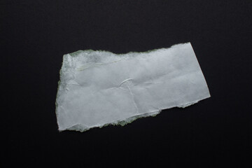 Creased white paper on a black background. Torn paper piece with copy space for text.