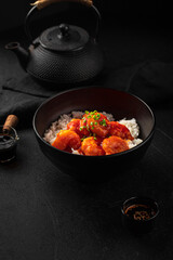 Portion of asian sweet and sour shrimp with rice on black background