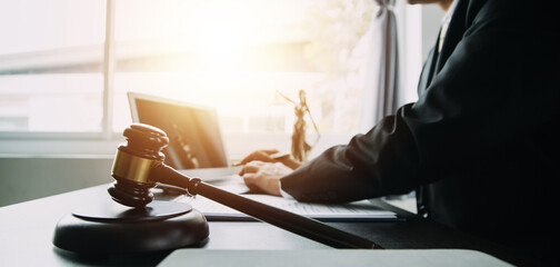 Justice and Law concept. Legal counsel presents to the client a signed contract with gavel and legal law or legal having team meeting at law firm in background