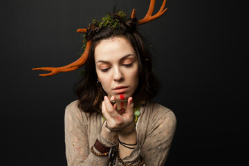 A portrait of a female druid or shaman with horns, holding ritual talismans in her hands on a black isolated background.Shamanic practices,Spiritual rituals,Pagan beliefs,Nature worship,Mystical.