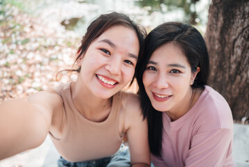 Smiling asian woman friends embracing each other in happy emotion, LGBT people lifestyles, spending time together on weekend.
