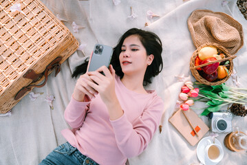 Young beautiful asian woman lie down for relax in the garden, spending time with beautiful nature, picnic on vacation summer time.